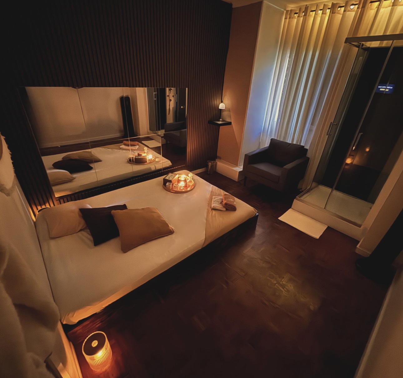 Sala de massagem privada com espelho de parede, tapete e velas no The Tantric Flow em Lisboa